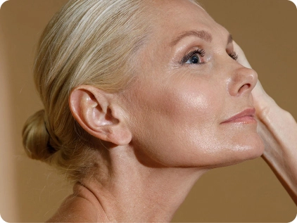 Mature woman with blonde hair touching face showing smooth skin and graceful aging in profile view