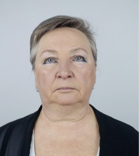 Middle-aged woman with short gray hair and blue eyes in black clothing against neutral background