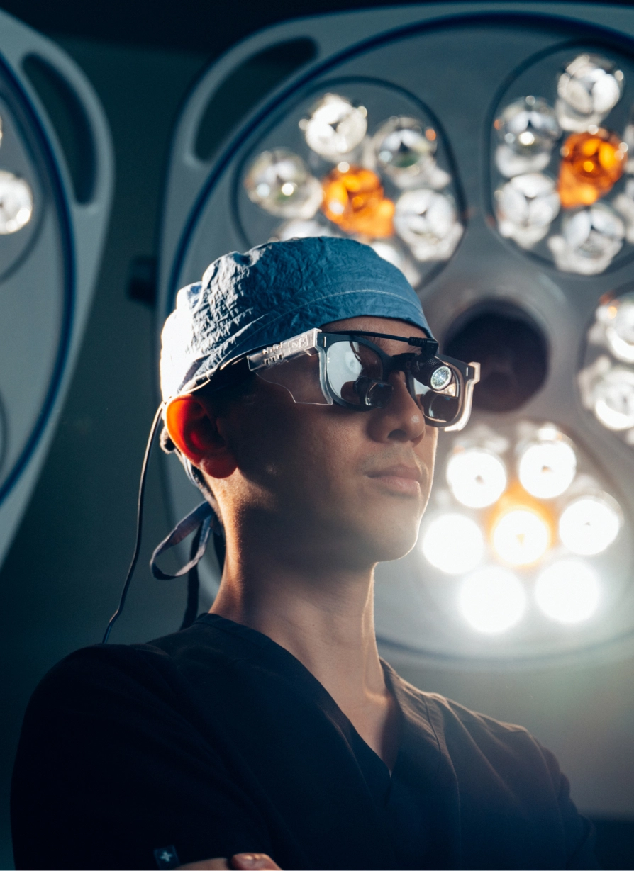 Young man wearing sunglasses and cap in front of illuminated carnival lights at dusk
