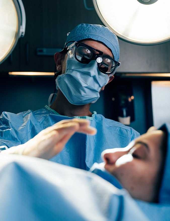 Surgeon wearing surgical mask and loupes performing medical procedure in operating room