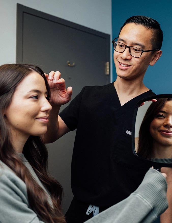 Professional makeup artist applying cosmetics to smiling female client in modern salon setting