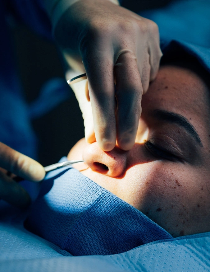 Dentist performing oral examination on patient with surgical light and dental instruments in clinical setting