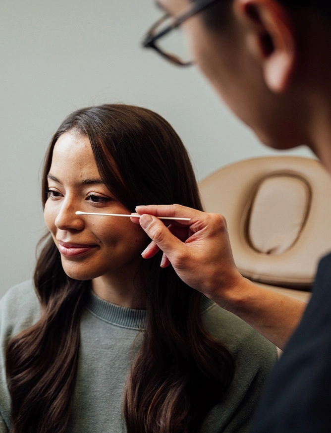 Professional makeup artist applying cosmetics to Asian woman's face during beauty session
